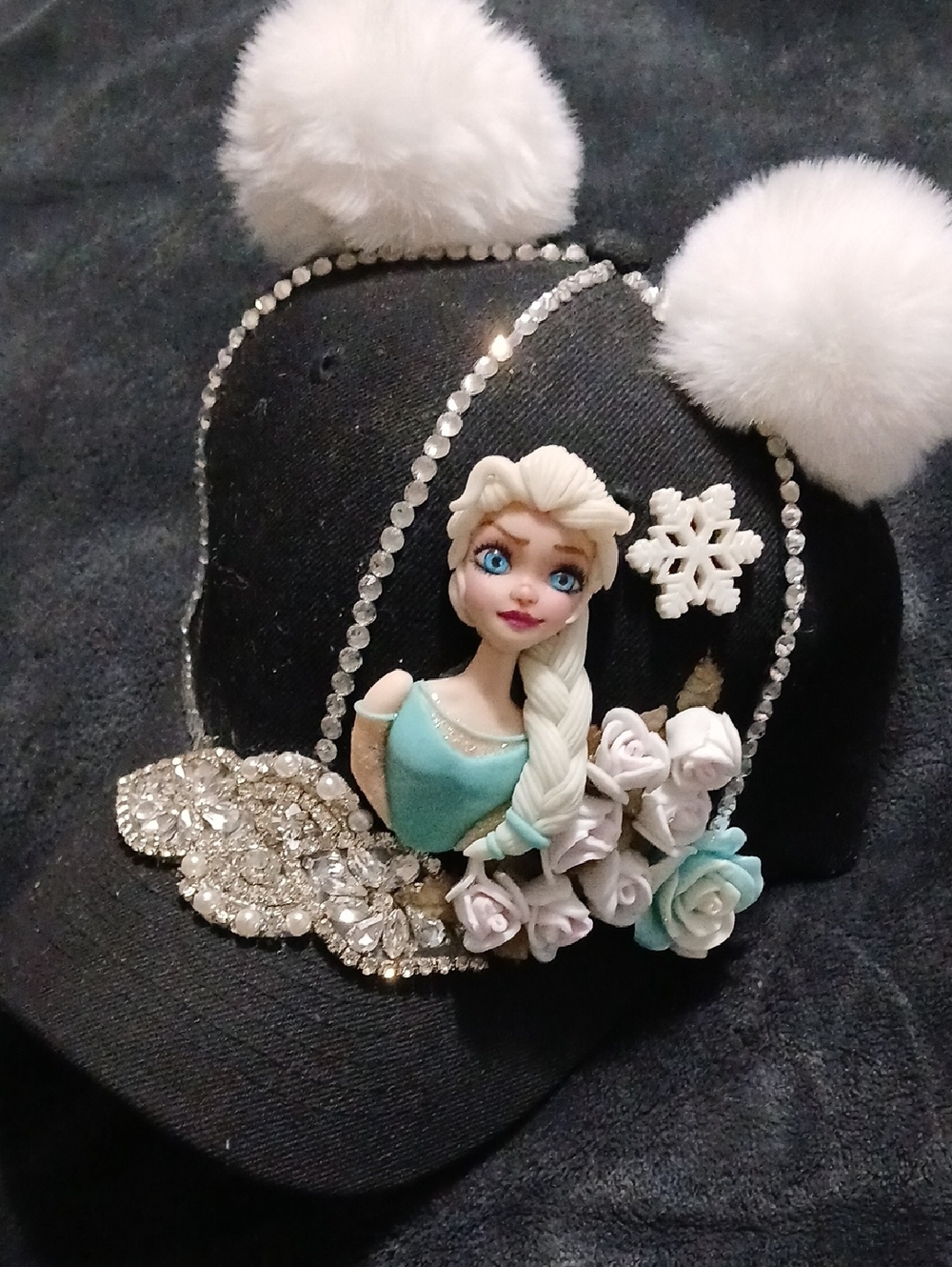 Embellished Black Cap with Elsa Figure and White Pom Poms